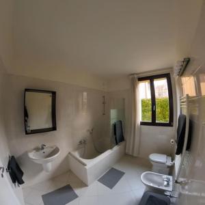 La salle de bains est pourvue d'un lavabo, d'une baignoire et de toilettes. dans l'établissement Residence Villa Olmo Como with Parking, à Côme