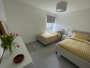 ein Schlafzimmer mit 2 Betten und einem Tisch mit einer Blumenvase in der Unterkunft Modern and Comfortable Flat with private parking in Oxford