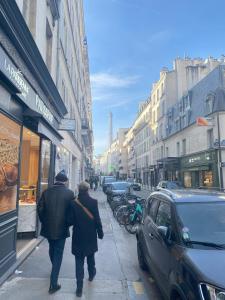 a couple of people walking down a city street at Super appartement 3T proche Tour Eiffel in Paris