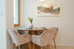 a table with four chairs and a vase of flowers at Apartament Garnizon z ogródkiem in Gdańsk