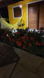 a flower garden with a hammock in front of a house at Pousada Céu Azul in São Miguel do Gostoso
