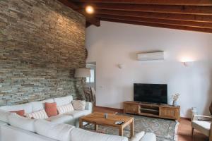Casa Nook Arrifana في ألخيزور: غرفة معيشة بأثاث أبيض وجدار من الطوب