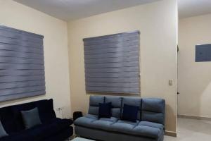 a living room with a blue couch and two windows at Confortable y Placentera Casa para la Familia in Ciudad Constitución