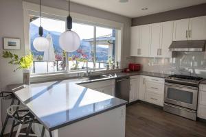 a large kitchen with white cabinets and a large window at Mountain Serenity Meets Luxury in Squamish
