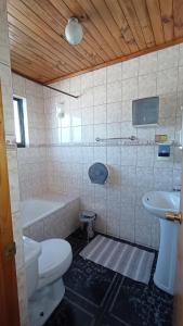 La salle de bains est pourvue de toilettes, d'une baignoire et d'un lavabo. dans l'établissement Lucerna Hostería, à Curanipe