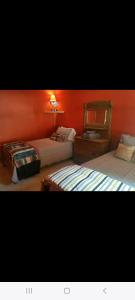 two beds in a bedroom with an orange wall at Sunset in Copake Falls