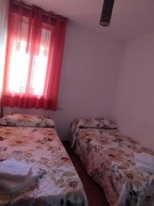 um quarto com 2 camas e uma janela com cortinas vermelhas em El Celemín em Benalup Casas Viejas