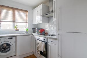 uma cozinha branca com uma máquina de lavar roupa e um frigorífico em 1 bed apartment central Hamilton free wifi with great transport links to Glasgow em Hamilton
