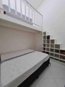 a white bedroom with a bed and a staircase at Casa em condomínio Juquehy in São Sebastião