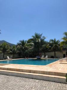 a swimming pool with palm trees in the background at Casa em condomínio Juquehy in São Sebastião