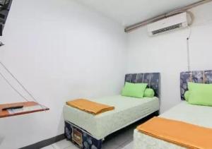 Habitación con 2 camas con almohadas verdes en Barrel Homestay, 4 mins Mentawai fast ferry, food, drink, sleep, transport by nginapdipadang en Padang