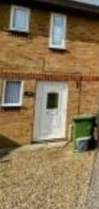 a brick house with two windows and a green trash can at Opera Home in Peterborough