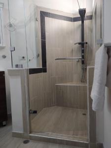 y baño con ducha y puerta de cristal. en Cozy 2-BR Apt with mountain view, en Medellín