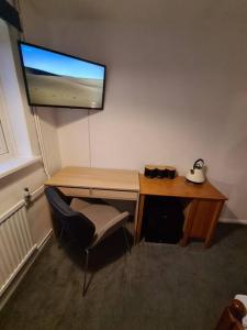 a wooden desk with a chair and a monitor on a wall at Spacious Rooms close to Aylesbury Centre - Free Fast WiFi in Buckinghamshire