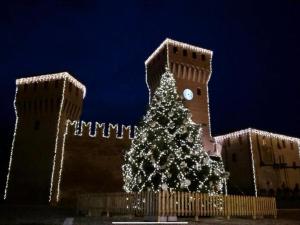 ein Weihnachtsbaum vor einem Gebäude mit einem Uhrturm in der Unterkunft Hotel La Torre in Formigine