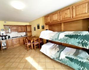 プラート・ネヴォソにあるPlain Soleil ski homeの二段ベッド2台とキッチンが備わる客室です。