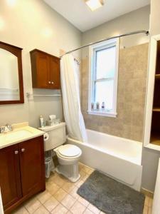 a bathroom with a tub and a toilet and a sink at Spacious Historic Apartments In Lakeview Chicago - Walk to Wrigley, Nightlife, Shops, Hospitals in Chicago +78 photos