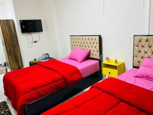 duas camas com lençóis vermelhos num quarto em Villa Fayrouz pyramids Inn no Cairo