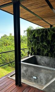 an outdoor bathtub on a deck with a view of the forest at Alma Tayrona Lodge in Los Naranjos