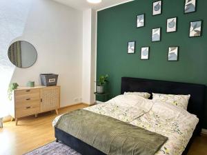 a bedroom with a bed and a green wall with pictures at Gemütliche 2-Zimmer Wohnung im Zentrum in Neumünster