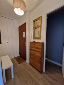 a room with a dresser and a mirror and a door at Appartement charmant bord de mer in Cabourg