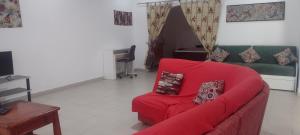 a living room with a red couch and a piano at Unique Owl Apartments in Sanyang