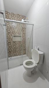 a white bathroom with a toilet and a shower at Pousada Casa Bella in Itaberaba