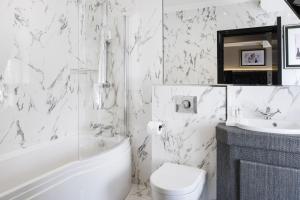 ein weißes Badezimmer mit einer Badewanne, einem WC und einem Waschbecken in der Unterkunft The Vermont ApartHotel New in Newcastle upon Tyne + 30 Fotos