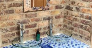 a bathroom with a glass sink in a brick wall at Mitanni in Santa Isabel