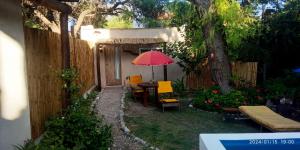 un patio con mesa, sombrilla roja y sillas en Monoambiente Colibrí en Capilla del Monte