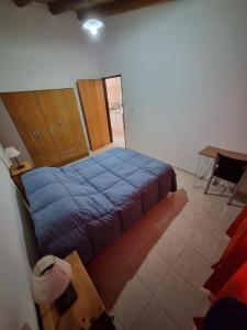 ein Schlafzimmer mit einem Bett mit einer blauen Decke in der Unterkunft Cuarta División Apartments in Malargüe + 6 Fotos