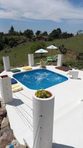 a swimming pool with chairs and umbrellas next to it at Cabañas & Suites "No es Fácil" in Villa Yacanto