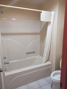 a bathroom with a white tub and a toilet at Howards Inn Motel in Eunice