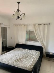 a bedroom with a bed with a chandelier and a window at Cabaña Holly Water in Cerro Azul