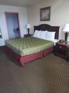 a large bed in a hotel room with two tables at Howards Inn Motel in Eunice