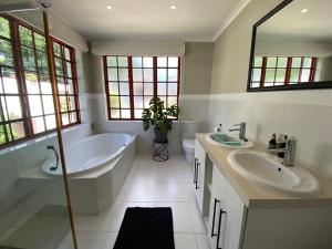Un baño con dos lavabos y una bañera y un tubo. en Garden Home in Upper Walmer, en Gqeberha 6 fotos más