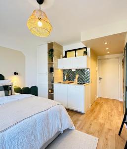 ein weißes Schlafzimmer mit einem Bett und einer Küche in der Unterkunft L’émeraude - Superbe studio tout équipé + parking in Metz