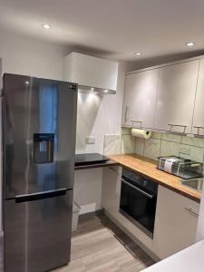 een keuken met een roestvrijstalen koelkast en een wastafel bij Cosy, self-contained guest house in Thornton Heath