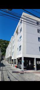 a large white building with a car parked in front of it at Apartamento em Pimenteiras in Teresópolis