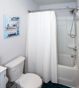 a bathroom with a toilet and a shower curtain at Cozy Coastal Home Near Beaches, Shops, Restaurants in Southport +25 photos