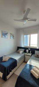 a bedroom with two beds and a ceiling fan at Beachfront Apartment La Manga in La Manga del Mar Menor +60 photos