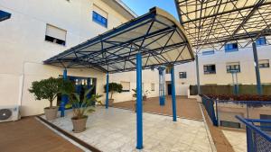 a building with blue poles and awning over a courtyard at AljaLux Sevilla Bormujos in Bormujos