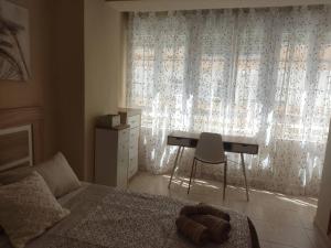 een slaapkamer met een bed en een bureau voor een raam bij Acogedor Apartamento frente al mar Elena y Michele in Almería