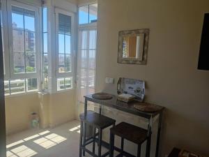 een kamer met een tafel en twee krukken en ramen bij Acogedor Apartamento frente al mar Elena y Michele in Almería