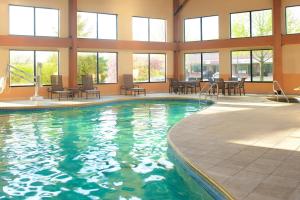 a swimming pool in a building with chairs and tables at Sheraton Bucks County Langhorne in Langhorne