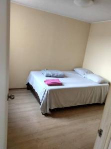 um quarto com uma cama com lençóis brancos e almofadas em Tait's House - Cómodo departamento Dúplex - Ate em Lima