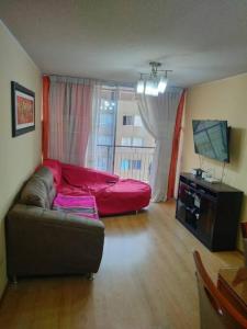 a living room with a red couch and a television at Tait's House - Cómodo departamento Dúplex - Ate in Lima
