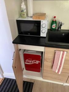 a kitchen counter with a cocacola microwave oven and avertisement at Cozy apartment next to Finnish culture spots in Helsinki