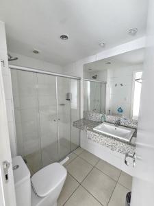 a white bathroom with a toilet and a sink at Flat Pampulha orla prox Mineirão in Belo Horizonte