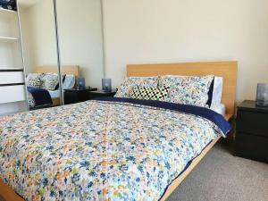 a bedroom with a large bed with a colorful comforter at Lovely City 1BR Apt Free Parking & Facing Mall in Canberra